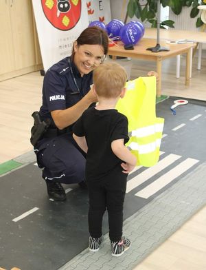 policjantka pokazuje dziecku kamizelkę odblaskową