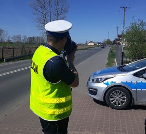 policjant z miernikiem prędkości stoi na drodze