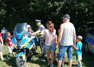 policjant stoi przy motocyklu a przy nim dzieci i dorośli