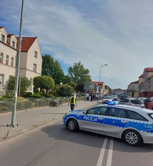 radiowóz na jezdni i  policjantka  w oddali idący uczniowie