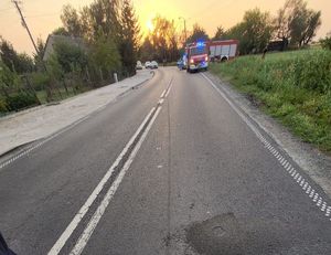 miejsce zdarzenia drogowego w oddali pracujące służby policji i straży pożarnej