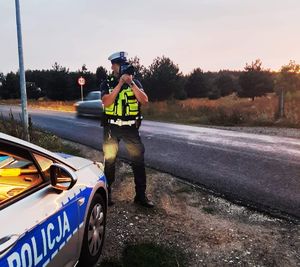 policjant sprawdza prędkość pojazdów na drodze