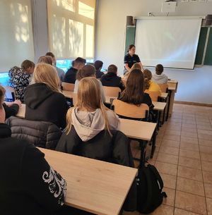 uczniowie siedzą w ławkach w tle policjantka