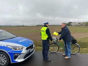 policjant przekazuje kamizelkę rowerzyście