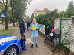 policjant przekazuje kamizelkę pieszej