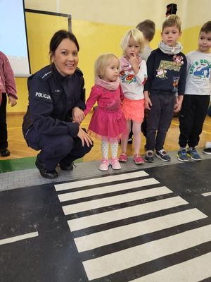 policjantka przeprowadza przez pasy dziecko