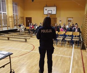 policjantka stoi przed grupą rodziców na sali gimnastycznej