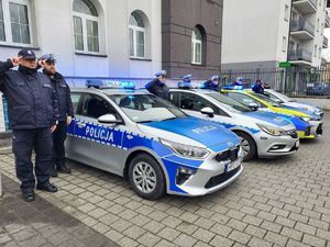 na pierwszym planie policjanci oddający hołd w tle radiowóz