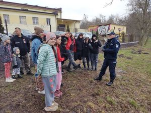 policjant stoi przed grupą ludzi i opowiada o pracy przewodnika