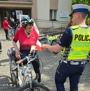 policjant przekazuje kamizelkę rowerzyście