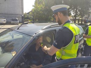 policjant sprawdza trzeźwość kierowcy siedzącego w pojeżdzie