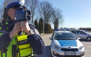 policjant mierzy prędkość, w tle radiowóz