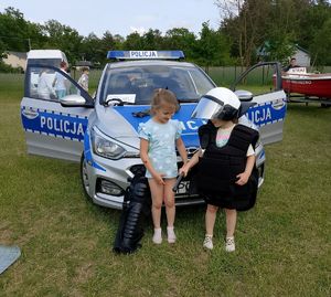 dziewczynki stoją przy radiowozie jedna ubrana w elementy munduru