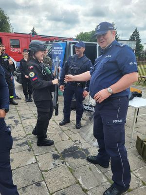 policjanci stoją obok nich kadetka ubrana w kamizelkę kuloodporną