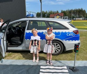 dziewczynki w strojach kujawskich przy radiowozie policyjnym