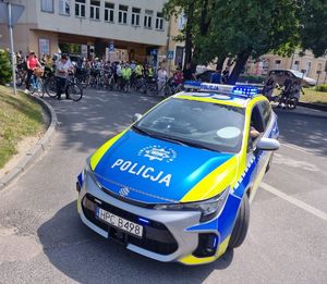 radiowóz za nim uczestnicy rajdu rowerowego