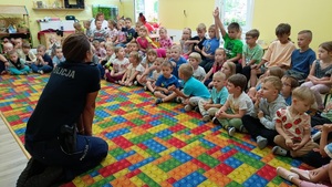 policjantka siedzi przed grupą dzieci