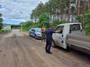 Policjanci wraz z funkcjonariuszami służby leśnej kontrolują kierowcę w rejonie leśnym