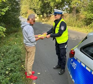policjantka wręcza kamizelkę odblaskową pieszemu