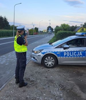 policjantka obserwuje drogę i mierzy prędkość w rejonie przejścia dla pieszych
