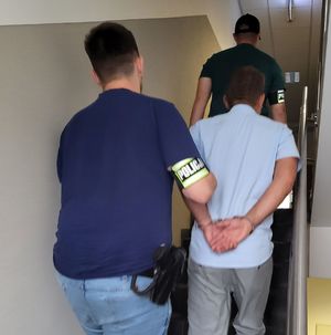 policjanci prowadzą zatrzymanego po schodach