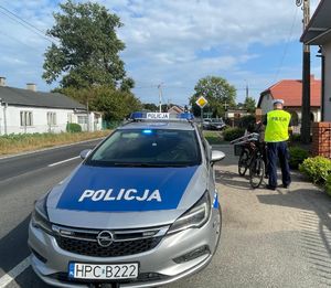 radiowóz a w tle policjant kontroluje rowerzyste