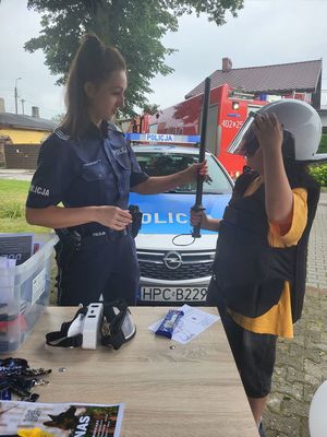 policjantka pomaga dziecku założyć policyjny kask