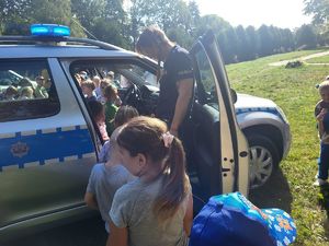 dzieci stoją przy radiowozie