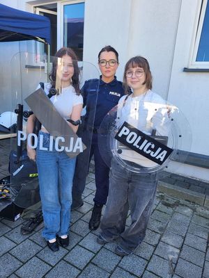 policjantka stoi z dziewczynami, które trzymają tarczę