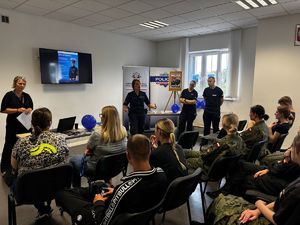 policjanci na sali przedstawiają zebranym prezentację na tv
