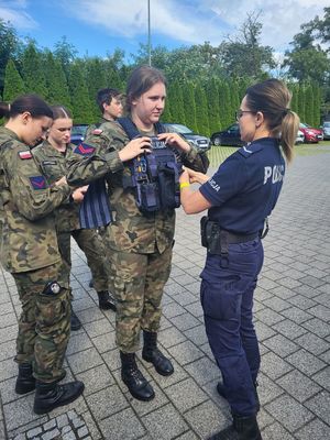 policjantka pomaga założyć uczennicy kamizelkę kuloodporną