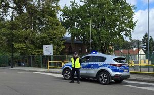 policjant stoi przy radiowozie