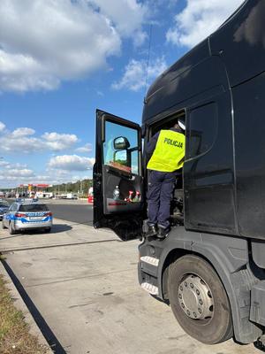 policjant stoi przed otwartymi drzwiami ciężarówki