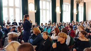 policjantka stoi z mikrofonem pomiędzy młodzieżą
