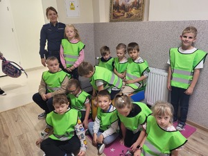 policjantka z dziećmi ubranymi w kamizelki odblaskowe