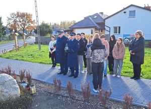 policjanci wraz z uczniami stoją przed tablicą upamiętniającą policjanta