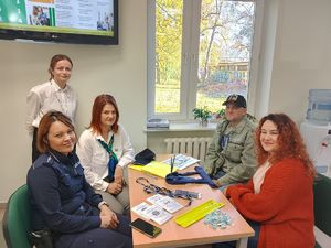 policjantka wspólnie z pracownikami ZUS siedzi przy stoisku profilaktycznym