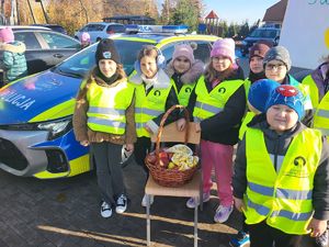 dzieci stoją z koszykiem jabłek i cytryn