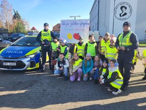 dzieci z policjantami stoją przy szkole