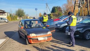 policjanci stoją przy pojeździe w którym siedzi kierowca