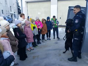 dzieci stoja z przewodnikiem psa i jego psem