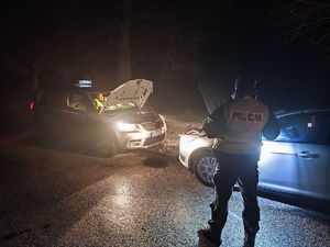 policjant stoi przy aucie, które jest podłączone do kabli