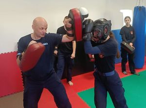 uczeń uderza w tarczę trzymaną przez policjanta