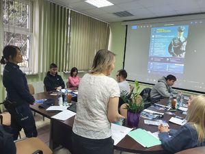 policjantka stoi przy biurku w tle wyświetla się prezentacja profil kandyydata