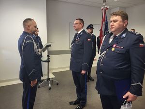 komendant wojewódzki stoi przed nowym i odchodzącym policjantem