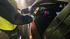 policjant podaje kierowcy urządzenie do kontroli trzeźwości