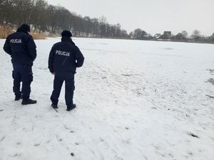policjanci stoją przy zamarzniętym brzegu jeziora