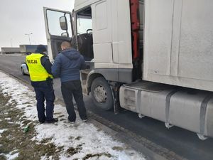 policjant stoi z kierowcą przy ciężarówce
