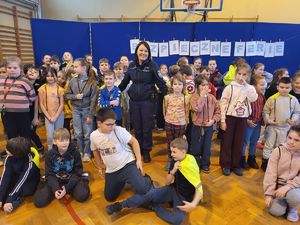 policjantka stoi z grupą dzieci ubranych w kamizelki