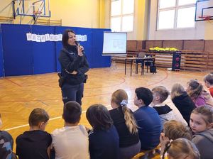 policjantka stoi z mikrofonem przed grupą dzieci